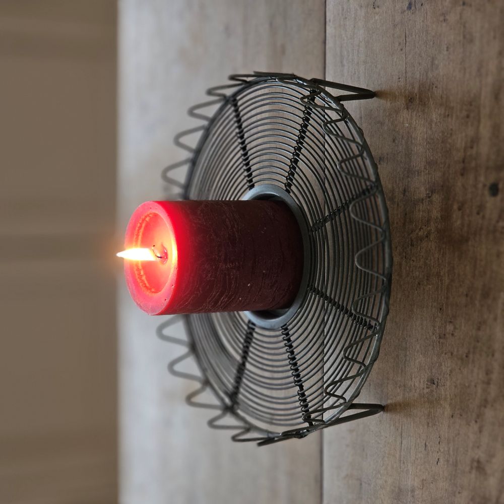 The French Wire Trivet Style Candle Holder merges vintage charm with primitive farmhouse simplicity. Featuring a gray metal wire base with a graceful wave-pattern border, it is inspired by old French wire cooling racks and trivets. 