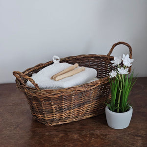 Wicker basket with a plant, white daffodils, and wooden items on a neutral background