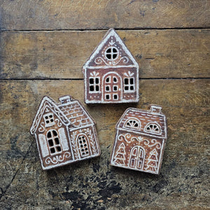 Our Gingerbread Village Shelf Sitter Set features three wooden houses with gingerbread inspired designs. Gingerbread house designs are replicated from original artwork painted onto burlap canvas, giving the art a unique depth and texture. Each house features cutout designs for the windows with coordinating natural wood on sides and backs. 