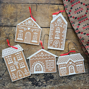 This Gingerbread Dutch Village Ornament Set makes a cheerful holiday accent. The set of five decorative ornaments comes in the shape of various gingerbread house designs. These seasonal ornaments feature natural wood with white color designs to give the appearance of icing decorated gingerbread. Designs are made with textured resin for a snowy detail. Each gingerbread house ornament hangs for display via attached twisted wire hangers with red ribbon accents.