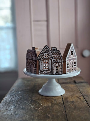 Our Gingerbread Village Shelf Sitter Set features three wooden houses with gingerbread inspired designs. Gingerbread house designs are replicated from original artwork painted onto burlap canvas, giving the art a unique depth and texture. Each house features cutout designs for the windows with coordinating natural wood on sides and backs. 