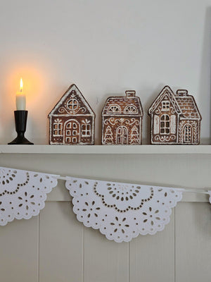 Our Gingerbread Village Shelf Sitter Set features three wooden houses with gingerbread inspired designs. Gingerbread house designs are replicated from original artwork painted onto burlap canvas, giving the art a unique depth and texture. Each house features cutout designs for the windows with coordinating natural wood on sides and backs. 
