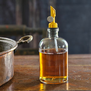 Add a vintage touch to your countertop cooking supplies with this Glass Apothecary Bottle with Weighted Pour Spout. This versatile bottle holds an ample amount of oil, vinegar, or any other cooking liquid. A weighted design does not require a long tube. The weight carries the liquid for a perfect pour every time. Features a golden metal and black rubber spout. This removable weighted pour spout keeps contents contaminant free. 