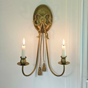 Experience the grandeur of vintage design with this ornate Gold Double Taper Candle Wall Sconce. Its aged gold finish and bow detailing bring a special ambience to any room. Perfect for adding a cozy atmosphere, this wall sconce holds two regular taper candles. 12.6"L x 6.5"W x 16.5"H