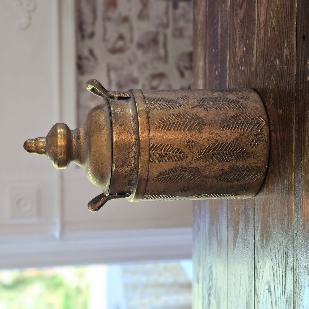 The Gold Embossed Leaf Canister adds a touch of elegance and vintage-style to any room. This decorative metal canister features a warm antique brass look with detailed embossed leaf and floral patterns. Each canister is topped with a decorative, tiered lid and side handles, making this a dramatic, eye-catching piece. For decorative use only. 7.5"Diam x 13"H