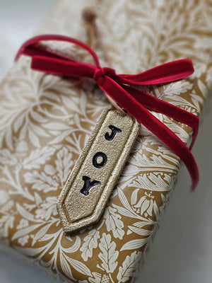 Enhance your holiday decor with our Gold Joy Tag Ornament Set. Each ornament features a durable leather loop for easy hanging and can be used to add a special touch to your gifts or adorn your tree. Celebrate the season with this elegant and versatile tag. Set of three.