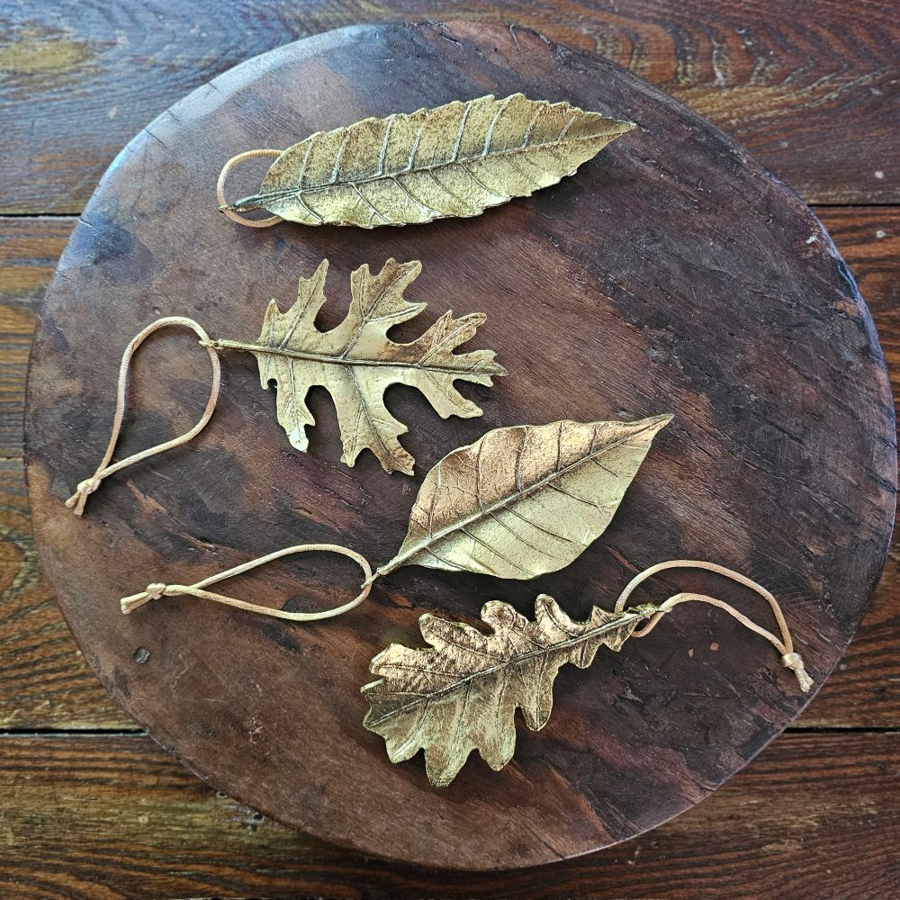 Add a magical touch this season with the Golden Leaves Ornament Set. The set of four exquisitely crafted leaves have a gold distressed finish that evokes timeless charm. Made from resin, each piece showcases delicate embossed details, adding rich texture and an elegant vintage allure. This set of four brings a refined touch to your seasonal celebrations. 