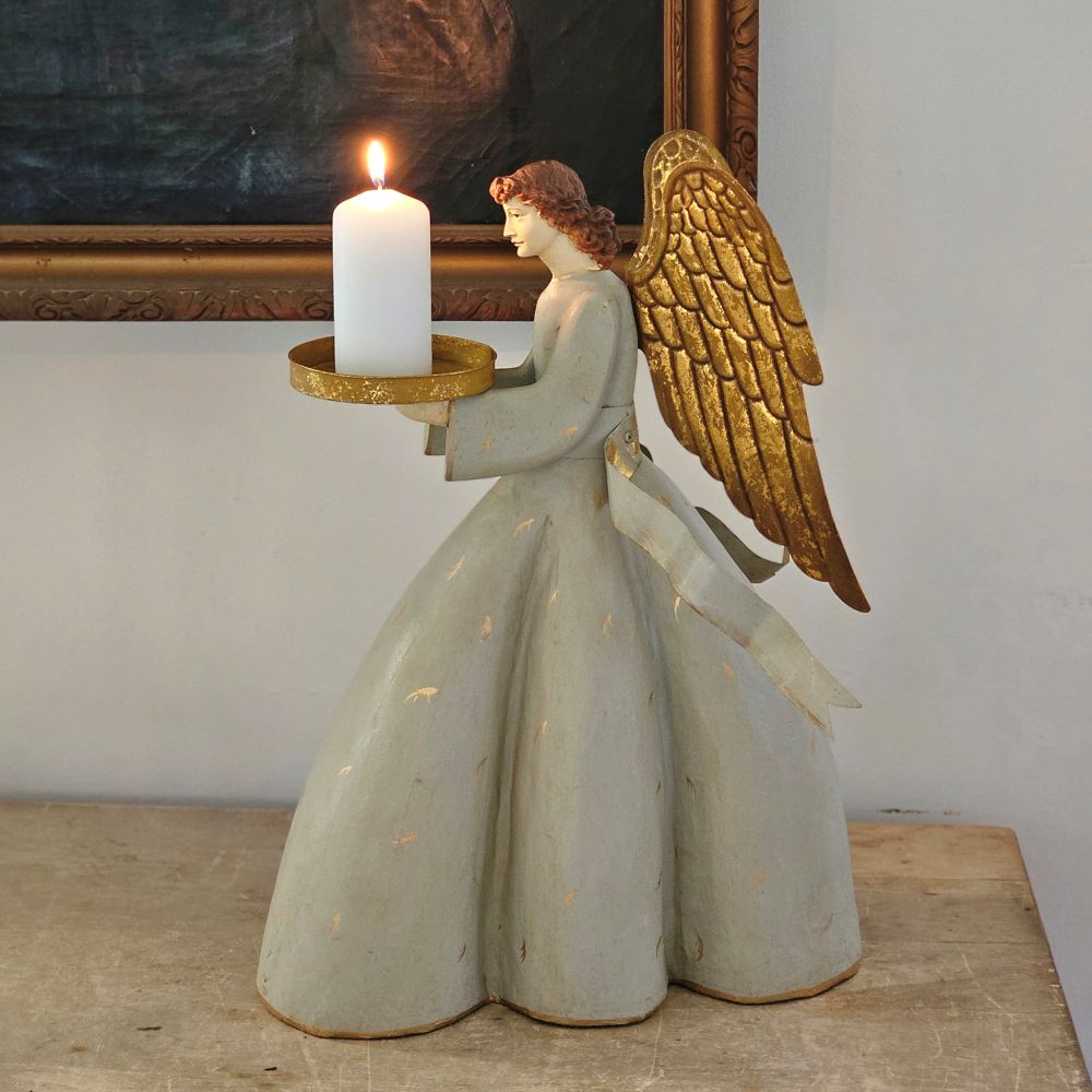 Introduce understated luxury to your decor with this Gold Wing Angel Candle Holder. Standing as a refined focal point, this sculptural piece marries functional candlelight with decorative sophistication. The aged gold winged design and chateau-gray dress offer French country charm. The golden tray holds a pillar candle up to 3" diameter. This eye-catching piece evokes the timeless elegance of heirloom treasures, making it a distinguished choice for discerning collectors. 