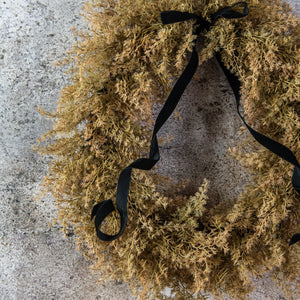 Enhance your seasonal decor with the sophisticated charm of our Golden Cypress Wreath adorned with a Black Velvet Ribbon. Crafted from faux cypress, this wreath offers a distinctive and refined look that brings a subtle, moody elegance to any doorway or interior space.19" Diam