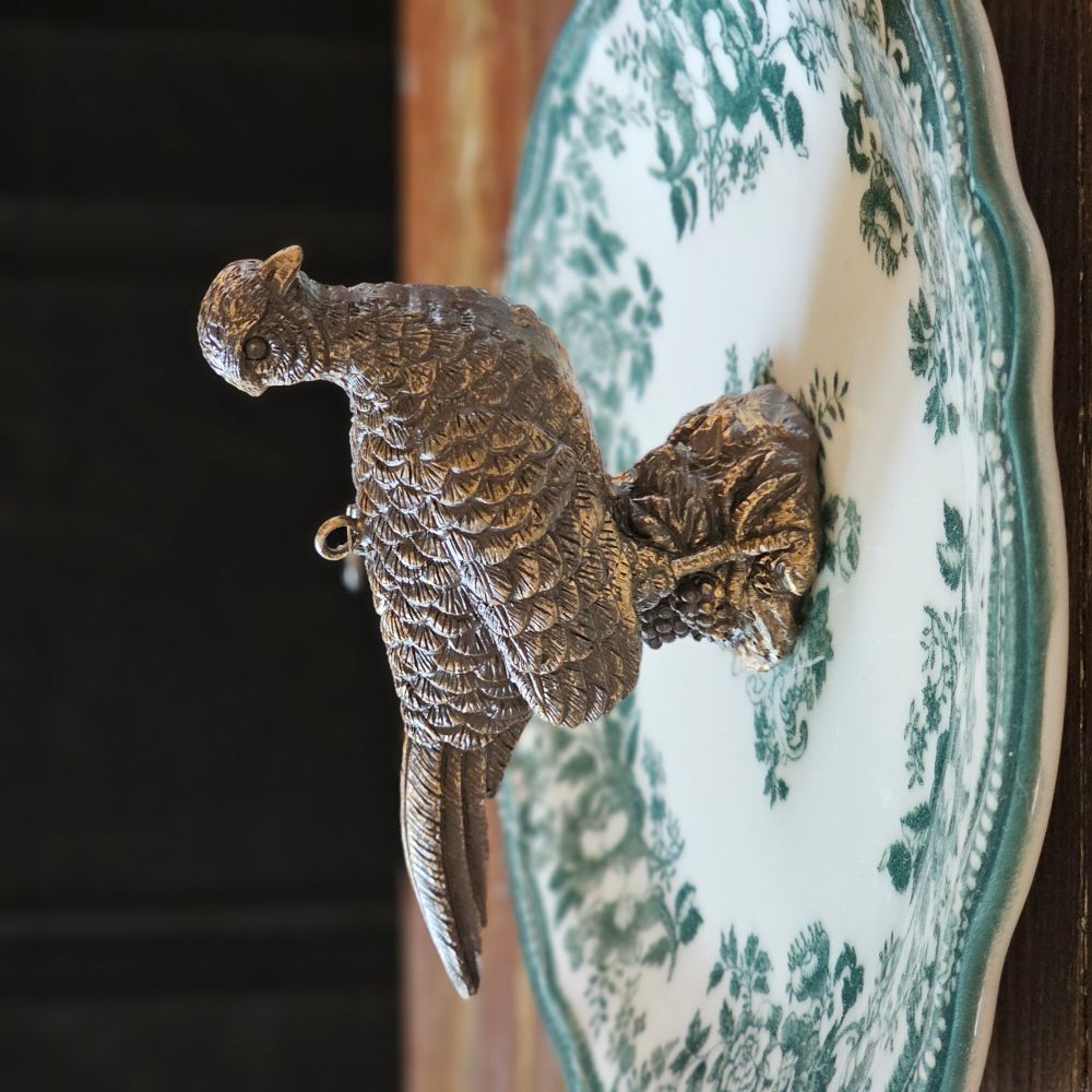 The Golden Pheasant Ornament features an artfully distressed gold finish and intricate feather detailing that evokes vintage charm and sophistication. Add timeless elegance to your tree or use as a gift topper. Made of resin and generously sized, it makes stunning nature-inspired display.