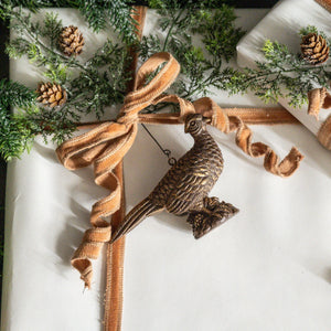 The Golden Pheasant Ornament features an artfully distressed gold finish and intricate feather detailing that evokes vintage charm and sophistication. Add timeless elegance to your tree or use as a gift topper. Made of resin and generously sized, it makes stunning nature-inspired display.