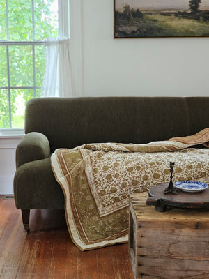 Enhance your guest room or reading corner with the elegant Golden Olive and Brown Block Print Quilted Throw. Showcasing a refined golden olive floral pattern accented in brown, it features a solid brown reverse side. Made from 100% cotton, this quilted throw offers both comfort and easy maintenance with machine wash-ability. Measuring 50”W x 60”H, it adds a touch of warmth and sophistication to any space.
