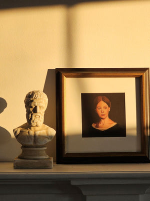 Framed portrait of a woman on a shelf with a classical bust