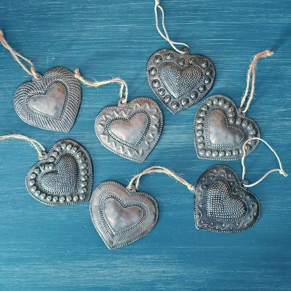 Each of these handmade Hammered Tin Heart Ornaments is a tiny work of art. These sweet milagro ornaments are heartfelt charms that symbolize love, hope, healing, and gratitude.
Sold as a set of seven, each heart is hand-cut, embossed, and painted with care. No two are alike — every set is a vibrant mix of colors and designs, perfect for spreading joy and inspiration. They make wonderful gift-toppers, ornaments, wall decor accents, or thoughtful tokens tucked into greeting cards or gift bags. 