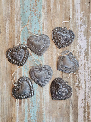 Each of these handmade Hammered Tin Heart Ornaments is a tiny work of art. These sweet milagro ornaments are heartfelt charms that symbolize love, hope, healing, and gratitude.
Sold as a set of seven, each heart is hand-cut, embossed, and painted with care. No two are alike — every set is a vibrant mix of colors and designs, perfect for spreading joy and inspiration. They make wonderful gift-toppers, ornaments, wall decor accents, or thoughtful tokens tucked into greeting cards or gift bags. 