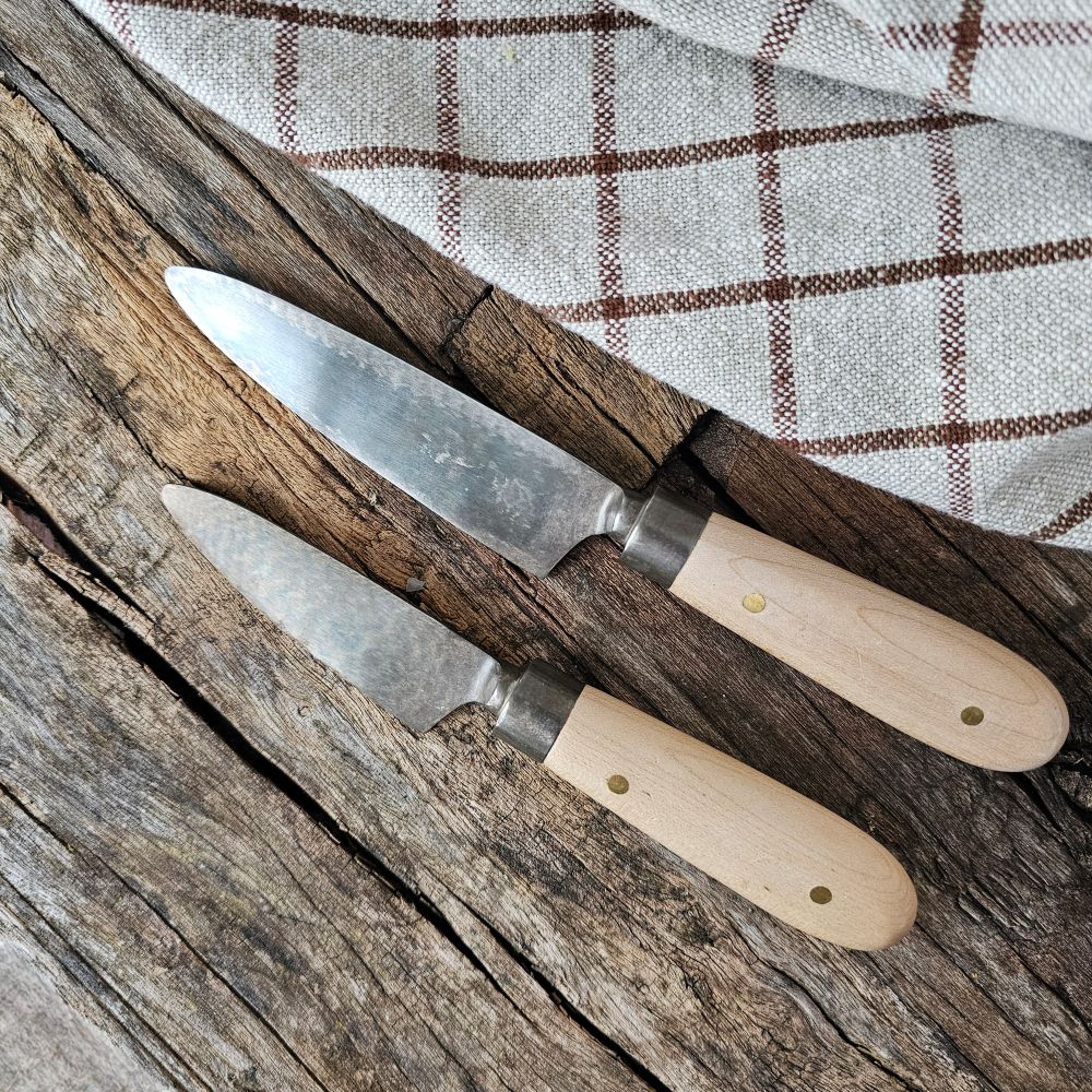 Upgrade your culinary tools with these Hand-Forged Cheese Knives. Featuring a combination of beechwood handles and stainless steel blades, these hand-forged knives offer precision and durability for everyday use. Beautifully packaged, they make a thoughtful hostess gift or a stylish addition to your flatware collection. Designed with sustainable materials and traditional crafting methods, these knives blend practicality with artisanal charm.
