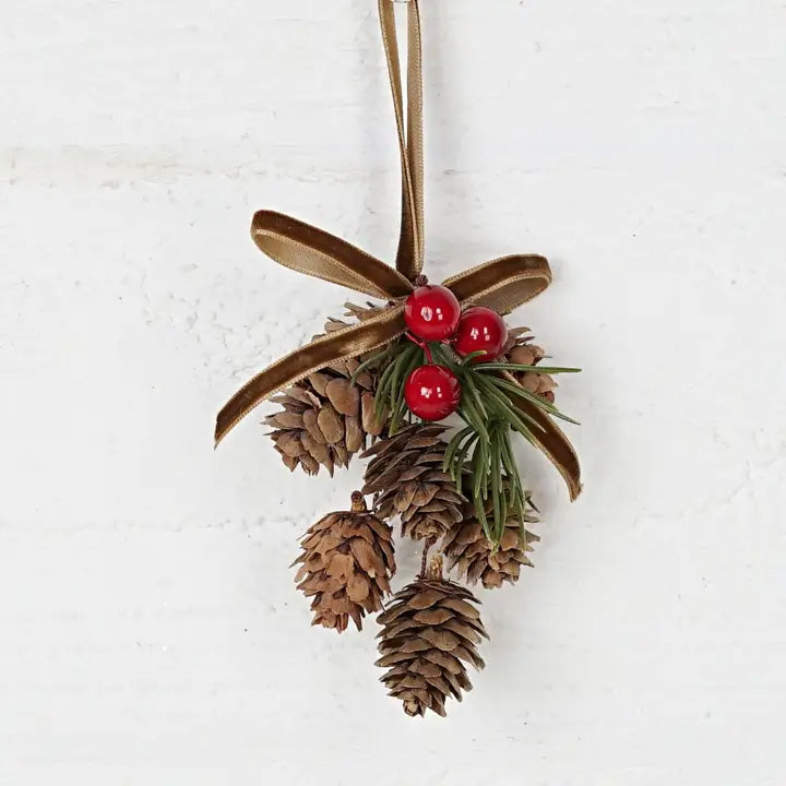 Add a touch of old-fashioned charm to your holiday decor with the Hanging Birchcones and Berries Ornament. Real birchcones beautifully contrast with faux red berries and a pine sprig adorned with a luxurious gold velvet bow. It's the perfect gift topper for a sophisticated and elegant touch. 2.5"W x 3"L