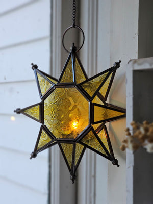 Let it glow! This charming Hanging Embossed Glass Star Candle Holder brings old-world ambiance to any room. This glass star light features embossed detail panes of yellow glass between an antiqued copper style metal framework. It holds one tealight candle (not included) and hangs from a chain. 