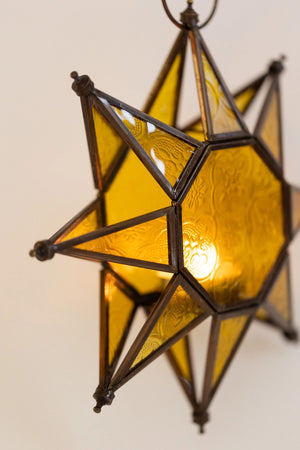 Let it glow! This charming Hanging Embossed Glass Star Candle Holder brings old-world ambiance to any room. This glass star light features embossed detail panes of yellow glass between an antiqued copper style metal framework. It holds one tealight candle (not included) and hangs from a chain. 