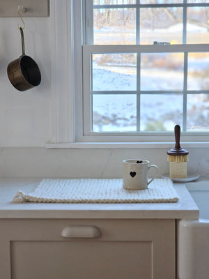 Every sip from our Rustic Heart Mug is a reminder to slow down and appreciate the simple things in life. This stoneware mug is the perfect shape to hold, and the hand-painted hearts spread a little love. Features a rustic light beige glaze with a raised black heart on the outer portion of the mug and a painted black heart on the inside as well.