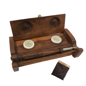 The Inkwell Stand with Porcelain Inkwells and Wood Nib Pen Set makes a perfect desk accessory reminiscent of early Colonial days. The set features a wood inkwell stand that opens and closes, two white porcelain inkwells, a wood nib writing pen, and a bag black ink powder so you can easily get started.