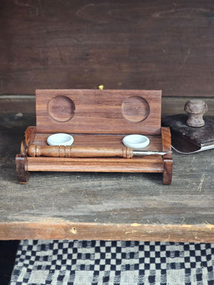 The Inkwell Stand with Porcelain Inkwells and Wood Nib Pen Set makes a perfect desk accessory reminiscent of early Colonial days. The set features a wood inkwell stand that opens and closes, two white porcelain inkwells, a wood nib writing pen, and a bag black ink powder so you can easily get started.