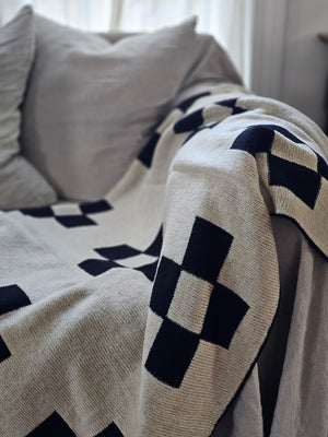 This Knit Reversible Cross Throw Blanket is made of a cozy wool blend, perfect for cuddling up on the couch. It features a unique reversible design with a beige and black cross geometric pattern that gives this throw handsome character with a vintage camp feel. Make this cozy throw part of your home decor for a timeless look and added comfort. 30% Wool, 70% Acrylic. Hand wash recommended. 50" x 60"
