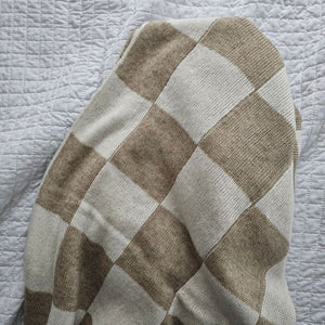 This Knit Beige and Cream Checkered Throw Blanket is made of a cozy wool blend, perfect for cuddling up on the couch. It features a unique reversible design with a beige and cream check pattern that gives this throw handsome character with a vintage camp feel. Make this cozy throw part of your home decor for a timeless look and added comfort. 