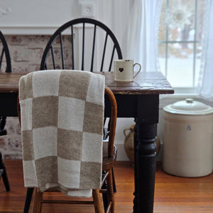 This Knit Beige and Cream Checkered Throw Blanket is made of a cozy wool blend, perfect for cuddling up on the couch. It features a unique reversible design with a beige and cream check pattern that gives this throw handsome character with a vintage camp feel. Make this cozy throw part of your home decor for a timeless look and added comfort. 