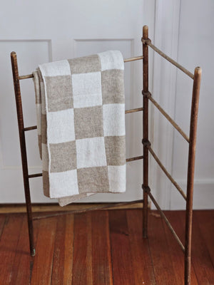 This Knit Beige and Cream Checkered Throw Blanket is made of a cozy wool blend, perfect for cuddling up on the couch. It features a unique reversible design with a beige and cream check pattern that gives this throw handsome character with a vintage camp feel. Make this cozy throw part of your home decor for a timeless look and added comfort. 