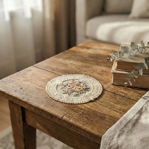 The Lace Embroidered Floral Coaster Set adds timeless elegance to coffee tables, vanities, and dining spaces. Designed with intricate lace detailing and a delicate floral embroidered center, this decorative coaster brings vintage-inspired charm to your home. The fabric construction helps absorb light condensation while providing a soft barrier between cups and surfaces. Ideal for everyday use or display, it combines romantic detailing with practical table protection. Set of four. 4.75" Diam