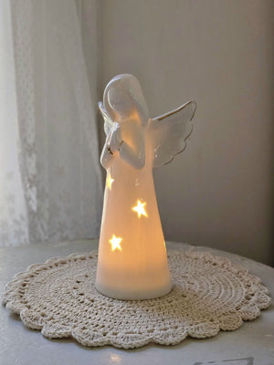 Enhance your home with the serene charm of our Lighted Ceramic Angel. Featuring a simple, organic design, this tabletop piece exudes understated elegance. Its clean white finish remains striking even without the gentle glow of the warm LED light, making it an ideal addition to both classic and modern farmhouse interiors. Requires two LR44 batteries (included). 6.25"H