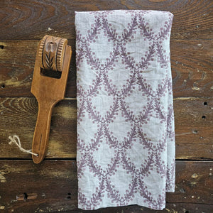 Add sweet English cottage charm to your kitchen with our Linen Tea Towel with Aubergine Floral Shield Design. This tea towel features a hand-drawn illustration inspired by British Shield designs and English decor. The combination of crisp oatmeal colored linen with the vintage plum colored shield design will brighten any home all season long. Includes one towel. 100% Linen. Made in the USA. 