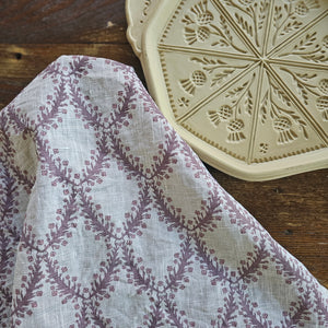 Add sweet English cottage charm to your kitchen with our Linen Tea Towel with Aubergine Floral Shield Design. This tea towel features a hand-drawn illustration inspired by British Shield designs and English decor. The combination of crisp oatmeal colored linen with the vintage plum colored shield design will brighten any home all season long. Includes one towel. 100% Linen. Made in the USA. 