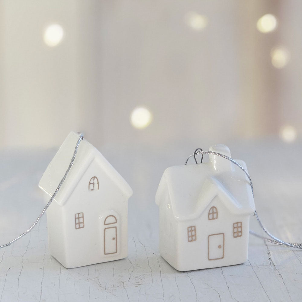 Add a delightful touch to your home with these Little Ceramic House Ornaments. The set of two houses are crafted from white ceramic with gold painted doors and windows, these small but sweet ornaments are perfect for topping off gifts or for hanging from the Christmas tree. They make adorable shelf accents all year long. Set of two. 