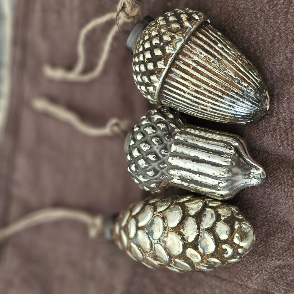 Add a magical vintage touch this season with our Mercury Glass Nuts and Pine Cone Ornament Set.&nbsp; The mirrored glass of each ornament has a distressed finish which captures the time-worn sparkle of vintage mercury glass. The aged, cloudy patina makes each feel just like an antique shop find. Perfect for any season, this Mercury Glass Nuts and Pine Cone Ornament Set will brighten your farmhouse or cottage. Features 3 aged glass ornaments with twine loops for hanging. Approximately 3" Diam x 4"H