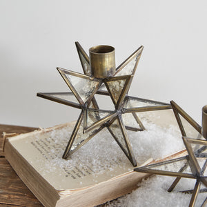 Let the twinkle of candle light reflect off this Mercury Glass Star Taper Holder Set of Two. The mirrored glass has a distressed finish, which captures the time-worn sparkle of vintage mercury glass. The aged, cloudy patina makes these taper holders feel just like an antique shop find, while the metal framework also has a vintage brass finish. Perfect for any season, these mirrored stars will brighten your farmhouse. Set of Two. 5½'' dia. x 4''H