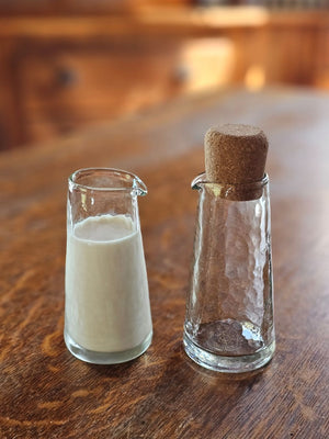 This Mini Glass Cruet, Set of Two, is a perfect choice for personalized servings of oil and vinegar, cream and milk, syrups, and more. Its petite size adds a sweet touch to your place settings. Beyond the kitchen, these charming vessels also serve beautifully as containers for your favorite bath oils or potions, offering a thoughtful touch of refinement wherever they’re placed. The gently pebbled glass surface enhances grip and visual appeal, making these carafes as practical as they are graceful.