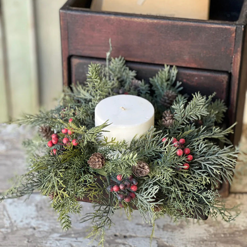 The Concord Christmas Candle Ring features a mix of faux cypress and pine greens, clusters of red berries and sweet little pine cones. This festive candle ring features a hint of frost on the greens for a wonderfully wintry feel. Perfect for adding an earthy touch to bows and basket with a candle tucked in. For 3" pillar candles. Candles and candle holders not included. 11” Diam with 3”inner