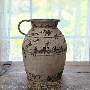 Bring old world charm to your farmhouse with this old style Rusty Milk Jug. This antique inspired reproduction features a highly distressed metal finish in a grey tan color with a rusty aged look . Perfect for bringing a bit of vintage flair to your farmhouse. 8" diam x 11.25"H