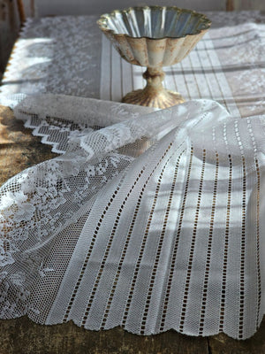 Our Old-World White Lace Table Runner adds a light and breezy touch of elegance to your home. This sheer lace runner has a dreamy quality and creates instant vintage charm that is perfect for country cottage living. Translucent white lace features a floral design inspired by old-world veils and scalloped edging. Blend of cotton, linen and polyester. 17.5”W x 47.24”L