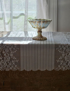 Our Old-World White Lace Table Runner adds a light and breezy touch of elegance to your home. This sheer lace runner has a dreamy quality and creates instant vintage charm that is perfect for country cottage living. Translucent white lace features a floral design inspired by old-world veils and scalloped edging. Blend of cotton, linen and polyester. 17.5”W x 47.24”L