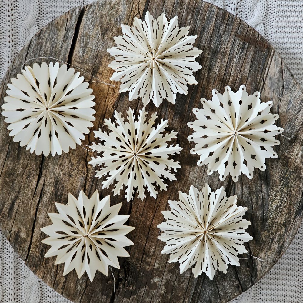 Capture the timeless elegance of winter with these exquisite paper snowflake ornaments. This curated collection of twelve delicate white cutouts evokes cherished seasonal traditions while adding refined charm to any holiday display. Each ornament features a convenient string hanger for effortless arrangement, allowing you to showcase these intricate designs throughout your home with grace and simplicity. Set of 12. Each is 4" in Diam