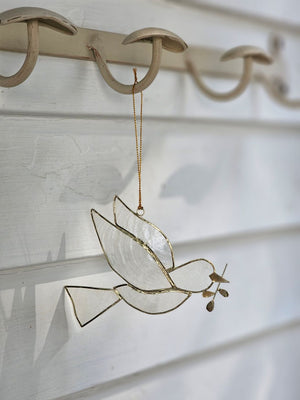 The Peace Dove Ornament, crafted from delicate capiz shell and accented with refined gold plating, adds an enchanted feel to any space. Its translucent glow brings a subtle, captivating charm, making it a graceful addition that enhances any space with a touch of serene elegance. Approximately 4.5"L x 3.5"H