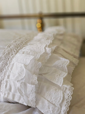 Our Petticoat Eyelet and Ruffles Pillow Sham brings shabby chic and farmhouse style together to create a dreamy white cottage bedroom. This Sham features a double layer of snow-white ruffle edges with exquisite floral eyelet detail and embroidered trim on both ends. This lace edge sham will add texture and a charming vintage look to your room.