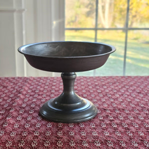 Add an antique touch to any tabletop with our Pewter Style Pedestal Compote. Perfect for displaying candles, holiday bobbles, potpourri and more. This metal pedestal features a pewter look with its aged and lightly distressed grey finish, giving this display riser a timeworn feel. For decorative use only. Candle and Candle Ring not included. 8.25”D x 6”H  