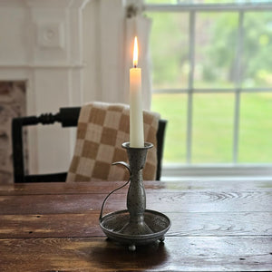 Add an antique touch to any tabletop with our Pewter Style Taper Chamberstick. This metal taper holder features a pewter look with its aged and distressed grey finish, giving this candle holder a timeworn feel. It has an embossed floral design on the tray, a long neck and a graceful handle. Bring Colonial period style to your farmhouse with this charming chamberstick. Candle not included