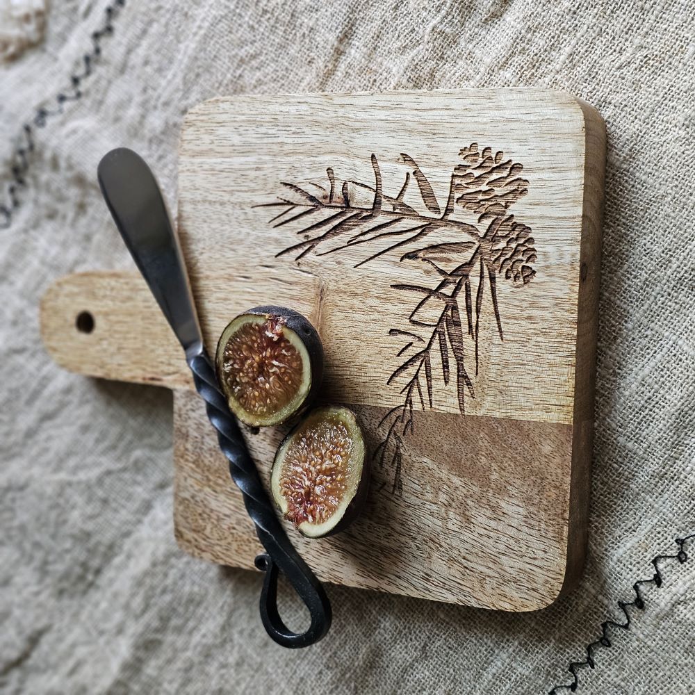 Expertly crafted with a rustic elegance, the Woodland Cutting Board with Iron Spreader is a versatile addition to your kitchen. This small board is perfect for cutting or serving and features an etched pine cone and needles design. The wood cutting board comes with the primitive iron spreader that features a twisted handle design for added rustic charm