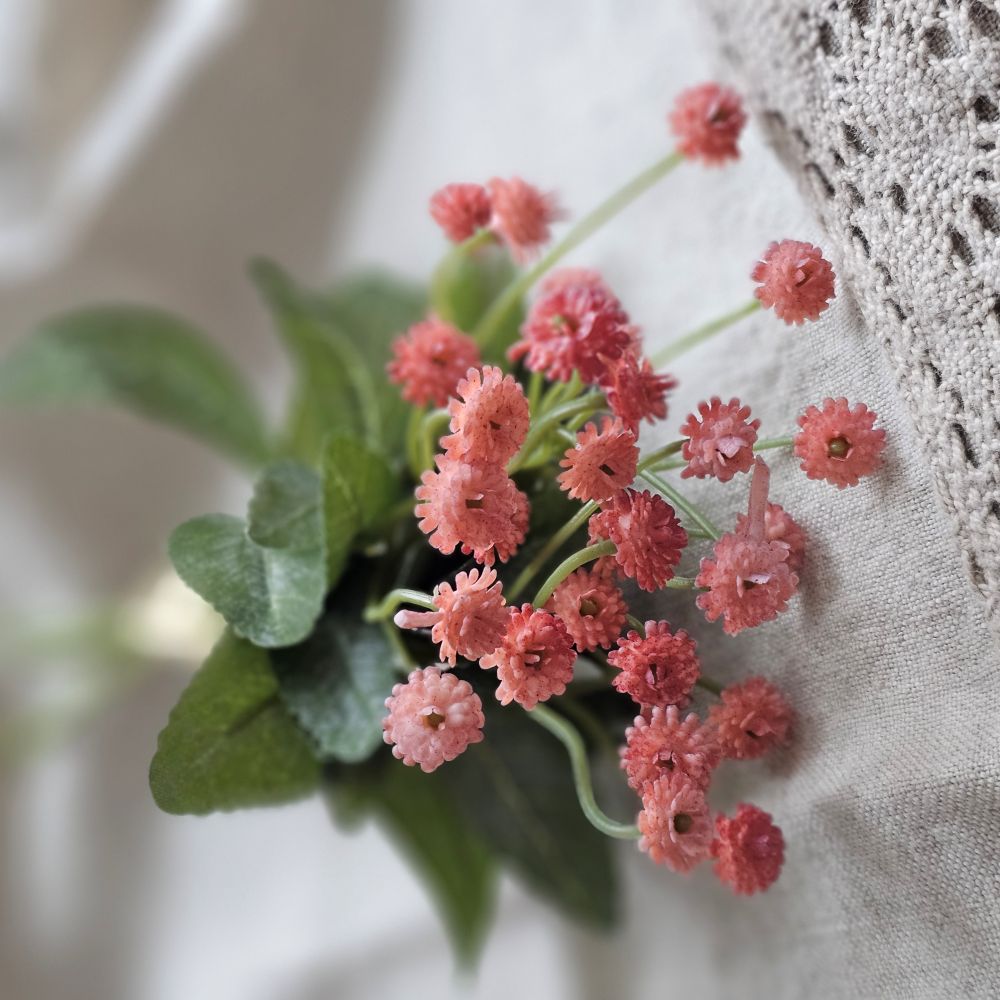 Let the garden spirit fill your farmhouse with this sweet Pink Mini Flower Bundle. This faux floral pick is lush and packed with delicate blossoms, making it an easy choice to fill any basket or vase. It bundle features three stems with small pink blossoms teeming with a natural verve. The forest green leaf accents add a fresh and realistic pop. 