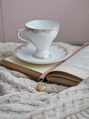 White teacup with gold lace design with Heart Locket Bookmark Braid.
